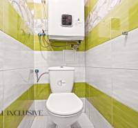A family house bathroom with green tiles and a toilet.