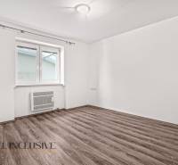 An empty room with white walls and a wood-patterned floor in a family house.