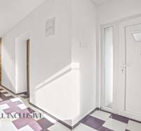 Entrance hallway of a family house with tiles, white walls, and wooden doors.