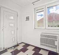 A hallway in a family house with white doors, a window, and tiles.