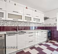 A kitchen in a family house with white cabinets, purple tiles, and built-in appliances.