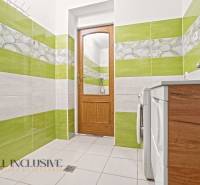 A bathroom in a family house with colorful tiles, wooden doors, and a washing machine.