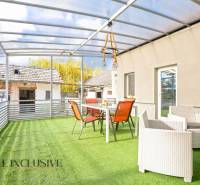 The terrace of a family house in Veľké Kosihy with a glass roof and furniture on artificial grass.