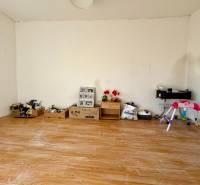 A room in a family house with walls covered in toys and a floor with a wooden decor.