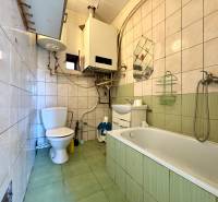 A bathroom in a family house with a bathtub, sink, toilet, and tiles with a color contrast.