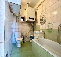 A bathroom in a family house with a bathtub, toilet, sink, and gas boiler.