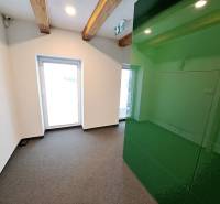 Office spaces with wooden beams and a green wall, carpeted floor.