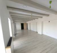 Empty office with white walls and wood-patterned flooring.