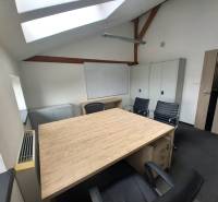 An office with a wooden floor, a skylight, and black chairs.