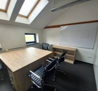 Office with chairs, a whiteboard, a table with a wooden decor, and skylights.