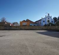A vacant residential plot in Nové Zámky, surrounded by historical buildings and a pharmacy.