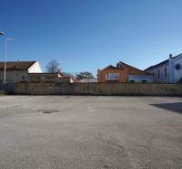 Urban space in Nové Zámky suitable for residential plots, surrounded by buildings and wooden houses.