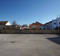 An empty asphalt space near a historic building in Nové Zámky, suitable for residential plots.