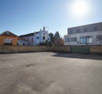 In Nové Zámky, there is an asphalt area surrounded by buildings on a plot suitable for housing.