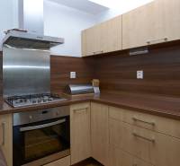 A kitchen in a 2-room apartment with a wood decor and a stainless steel range hood.