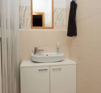 Bathroom with a mirror and a sink above a cabinet in a 2-room apartment.