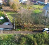 Plots - housing on M.H. Chvotekova Street in Dolna Krupa, with greenery and a parked car.