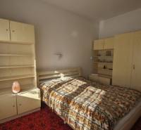 A bedroom in a family house with light furniture and a patterned bedspread.