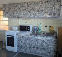 A kitchen with tiles, a stove, and a fireplace in a family house, with a wooden decor floor.