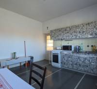 A kitchen in a family house with a stove and kitchen cabinets, floor with wooden decor.