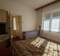 A bedroom in a family house with a television and floral patterned bed linen.