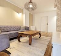 Living room in a 3-room apartment with a sofa, wooden table, and wooden decor flooring.