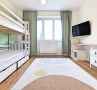 A room in a 3-room apartment with a bunk bed, a television, and a floor with a wooden decor.