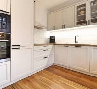 A kitchen in a 3-room apartment with white cabinets and a wooden decor floor.