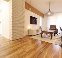 Living room in a three-room apartment with a wooden decor floor and brick cladding on the wall.