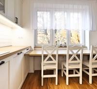 Dining area in the kitchen of a 3-room apartment, floor with wood decor, white cabinets.