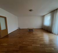 Spacious living room with wooden flooring and windows in a 3-room apartment.