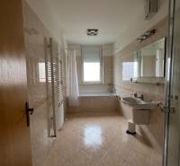Bathroom in a 3-room apartment with a bathtub, glass shower enclosure, and light tiles.