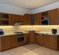 A kitchen unit in a 3-room apartment with wooden cabinets and appliances, light brown tiles.