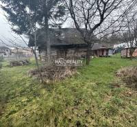 An older wooden house surrounded by a grassy plot with fruit trees intended for living.