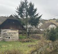 A wooden cottage by the stream, surrounded by trees, grass on the property - living in the countryside.