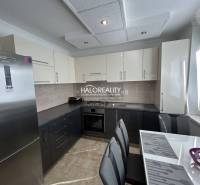 A kitchen in a 2-room apartment with a wood-patterned floor and light cabinets.