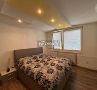Bedroom in a two-room apartment with a wooden decor floor and a large upholstered bed.