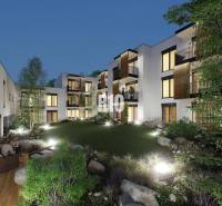 In Žilina on Dolná Street, there are illuminated apartment buildings surrounded by greenery and a terrace.