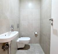 Bathroom in a 2-room apartment with a toilet, sink, and tiles in neutral shades.