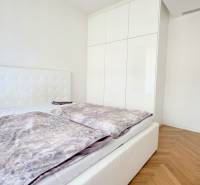 Bedroom in a 2-room apartment with a bed, white wardrobe, and wooden decor flooring.
