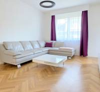 Living room with a corner sofa, purple curtains, and a wooden decor floor in a two-room apartment.