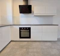 A kitchen in a 2-room apartment with white cabinets and a black sink.