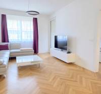 A bright living room in a two-room apartment with a wooden decor floor and a corner sofa.