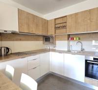 A kitchen in a 3-room apartment with a wooden decor floor, equipped with a dishwasher and an oven.