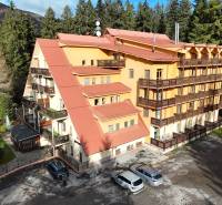 A building in Donovaly Spiežovec surrounded by forests, a parking lot with cars.