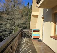 A balcony with a view of the forest from a 3-room apartment in Donovaly with cowbells.