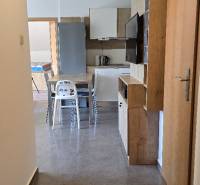 Interior of a 3-room apartment with wood-patterned flooring and a kitchen with appliances.