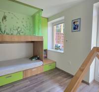Children's room with wood-patterned flooring, colorful furniture, and a view of the forest.