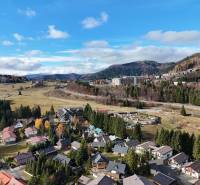 View of Donovaly with forests and houses, offering 3-room apartments.