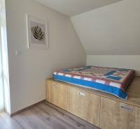 Cozy bedroom in a 3-room apartment with wood-patterned flooring and a view of nature.